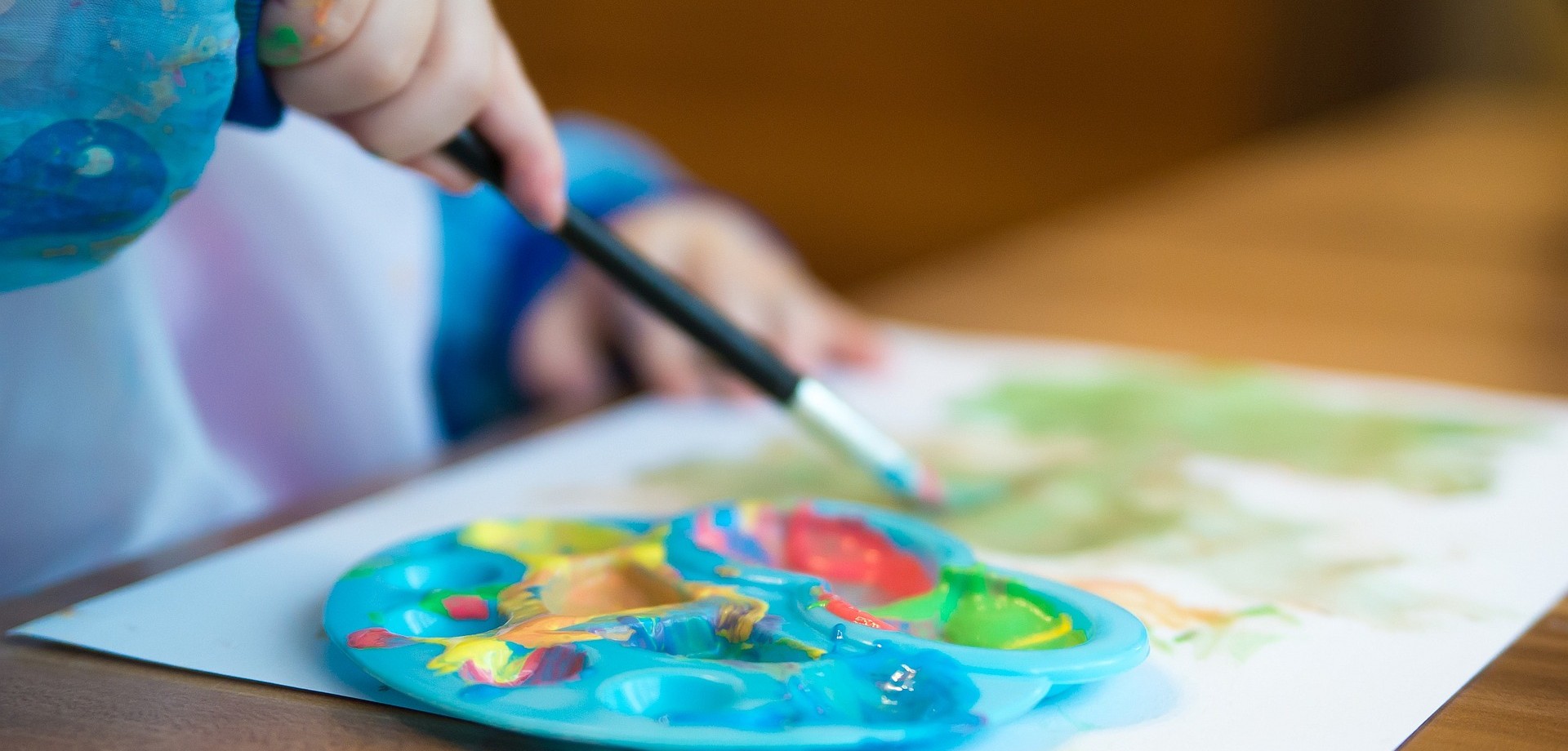 Ein Kind malt mit knallbunten Farben.
