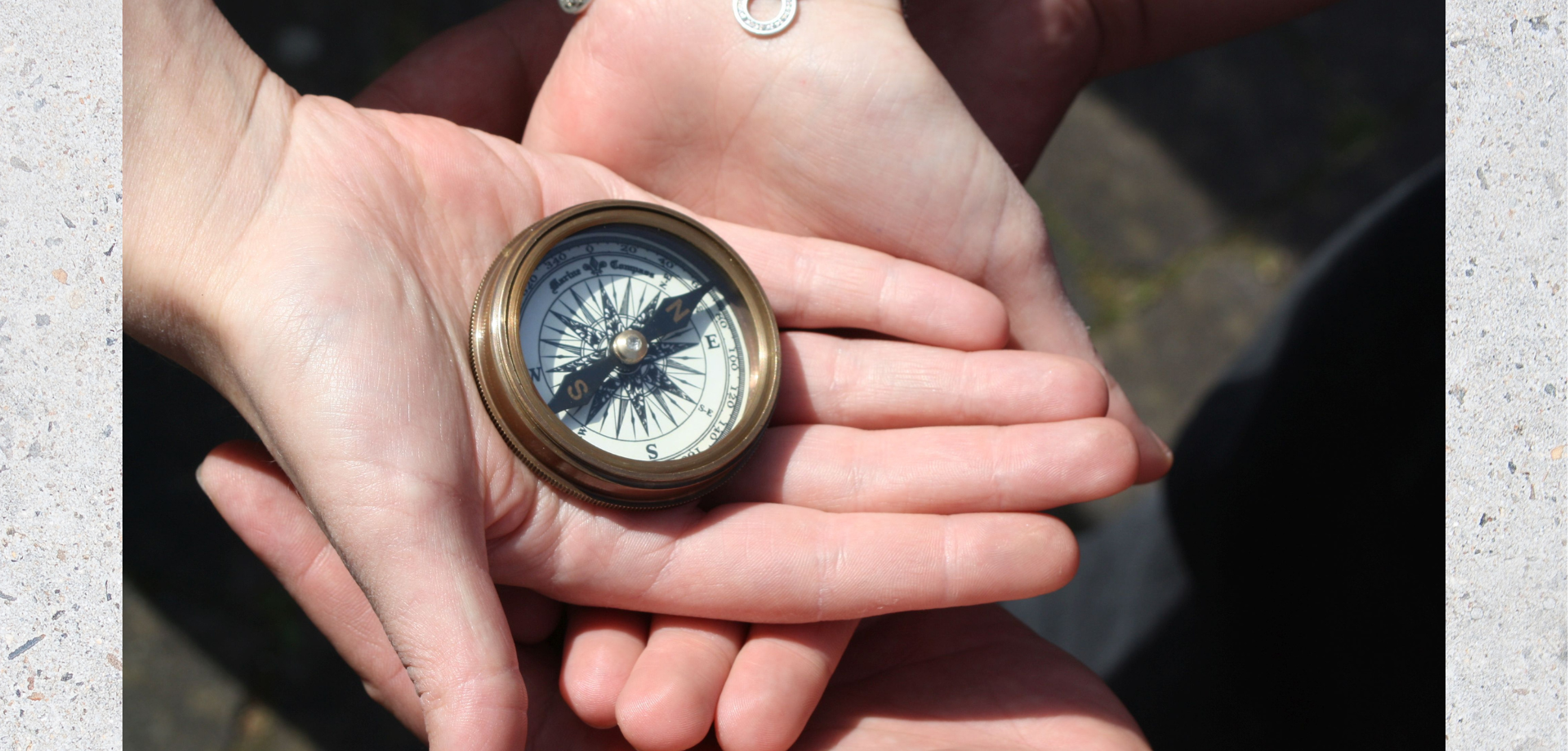Das Bild zeigt Hände, in denen ein kleiner Kompass liegt.