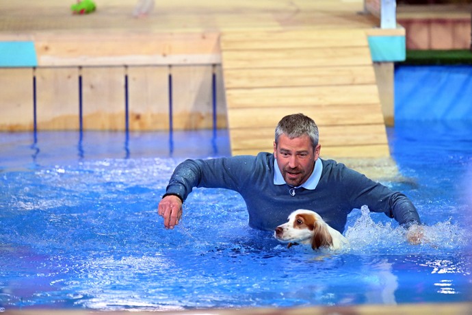 Das Bild zeigt einen Kollegen mit seinem Hund bei einem Parcous in einem Schwimmbecken.
