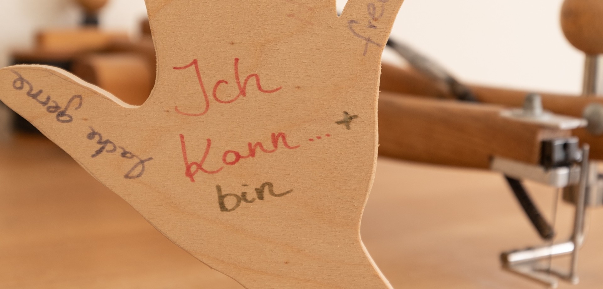 Eine in der Ergotherapie gebastelte Holzhand, auf der der Spruch "Ich kann" steht, steht auf einem Tisch.