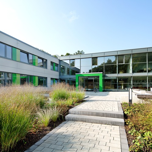 Das Bild zeigt ein großes Glasgebäude, mit einem grün gerahmten Eingang,das den Haupteingang der Klinik in Marl darstellt.
