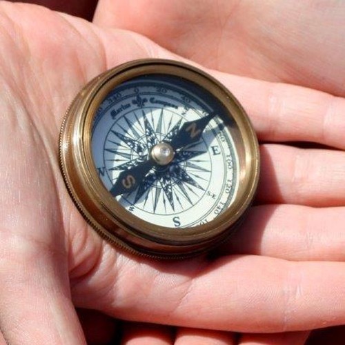 Das Bild zeigt eine Hand, in der ein kleiner Kompass liegt.