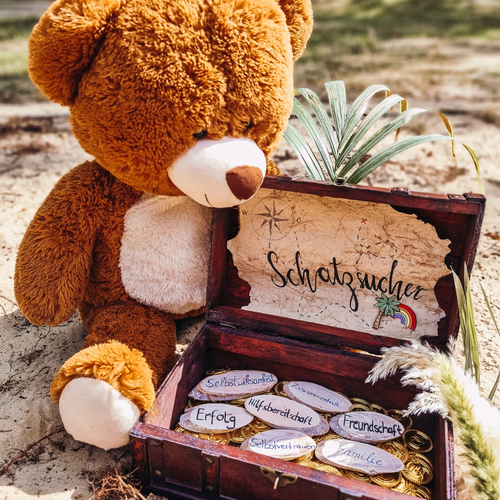 Das Bild zeigt einen Teddybär, der eine kleine braune Schatzkiste öffnet.