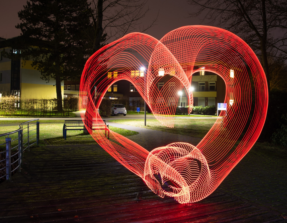 Das Bild zeigt ein rotes leuchtendes Herz, das mit der Technik Lighpainting erzeugt wurde.